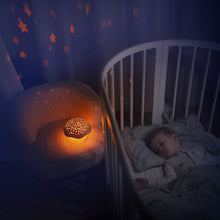 Load image into Gallery viewer, Lifestyle shot of a Pabobo Musical Stars Projector (mushroom design) casting a calming, warm star projection on the wall and furniture next to a child sleeping in a round crib.
