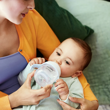 Load image into Gallery viewer, Baby drinking from Philips Avent Natural Response Trainer Cup while being held by a parent.
