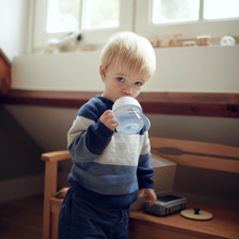 Load image into Gallery viewer, Toddler holding and drinking from Philips Avent Natural Response Trainer Cup in a cozy room.
