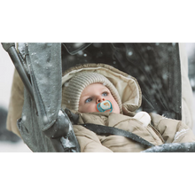 Load image into Gallery viewer, A toddler in a stroller wearing winter gear and using a blue tiger-themed Philips Avent Ultra Air Nighttime soother (SCF376/32) in the snow.
