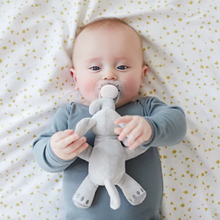 Load image into Gallery viewer, Overhead view of a baby holding a Philips Avent ultra soft snuggle elephant plush pacifier, available with free delivery across Malta &amp; Gozo.
