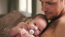 Load image into Gallery viewer, A father holding his newborn baby who is using a lavender Philips Avent Starter soother designed for infants 0–2 months.
