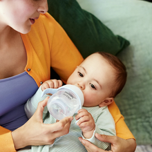 Load image into Gallery viewer, Baby drinking from a Philips Avent Natural Response Trainer Cup with easy-grip handles
