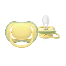 Load image into Gallery viewer, A close-up of a soft yellow Philips Avent Ultra Air soother for toddlers 18 months and older, featuring large airholes for skin ventilation and a clear silicone nipple.
