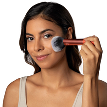 Load image into Gallery viewer, Woman using the fluffy, copper-handled Real Techniques Powder Brush (RT 201) to apply setting powder or blush onto her cheek for a smooth, airbrushed finish.
