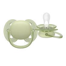 Load image into Gallery viewer, A side view of a clear pacifier highlighting its rounded shield designed to minimize pressure on a baby's cheeks.
