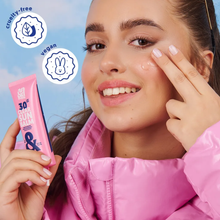 Load image into Gallery viewer, A smiling woman applying the Clear Sun Balm with icons for vegan and cruelty-free certification.
