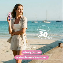 Load image into Gallery viewer, A woman on a beach holding the Clear Sun Balm, showcasing its velvety, water and sweat-resistant texture.
