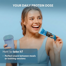 Load image into Gallery viewer, A smiling woman in fitness apparel holding a Vitaldin coconut protein bar and a shaker bottle, with text suggesting it as a perfect snack between meals or training sessions.
