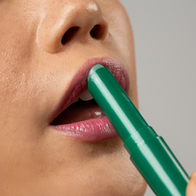 Load image into Gallery viewer, Close-up of WICKED x Dr. PAWPAW Enchanting Lip Balm being applied directly to the lips, showing the green balm stick designed to develop a personalised pink tint.
