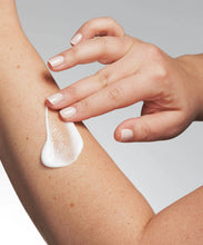 Load image into Gallery viewer, Close-up of a hand applying the white moisturizing lotion to the skin on an arm, demonstrating lotion application for dry skin.
