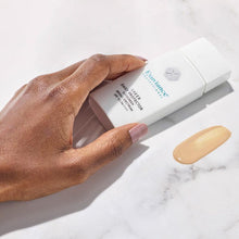 Load image into Gallery viewer, Hand holding the Exuviance Professional Sheer Daily Protector SPF 50 bottle, showing a tinted swatch of the lightweight sunscreen on a marble surface, suggesting seamless application.
